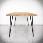 Träbord med smala svarta ben på stengolv.