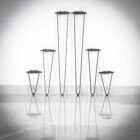 Sju svarta metallstativ mot vit vägg.