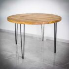 Runt träbord med metallben på stengolv.