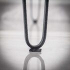 Närbild av metallbordsben mot vit yta.