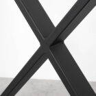 Svart metallben i korsform på bord.