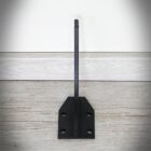 Metallstödfäste på trägolv och vit vägg.