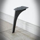 Svart metallben mot trägolv och vit vägg.