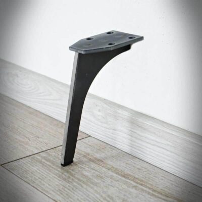 Svart metallben mot trägolv och vit vägg.