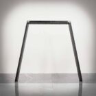 Svart metallben till bord mot vit vägg.