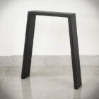 Svart bordsben på grått golv.