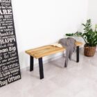 Träbänk med filt och växt i hörnet.