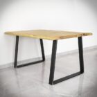 Rektangulärt träbord med metallben på stengolv.