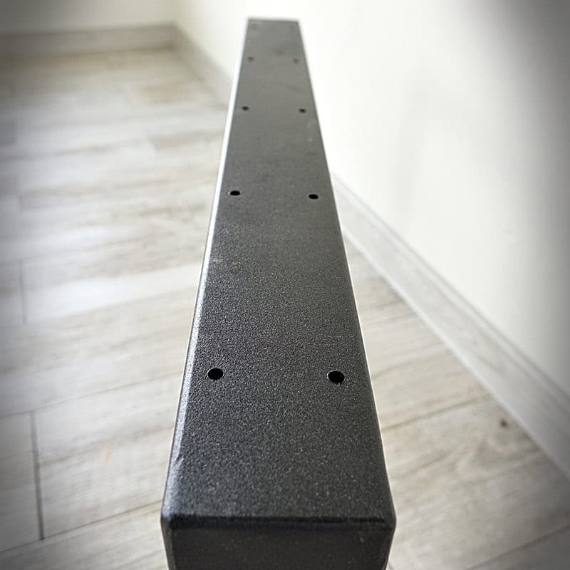 Svart metallbalk på ljus golv.