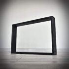 Svart rektangulärt bordsben på träyta.