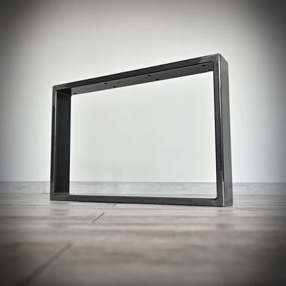 Metallram på trägolv mot vit vägg.